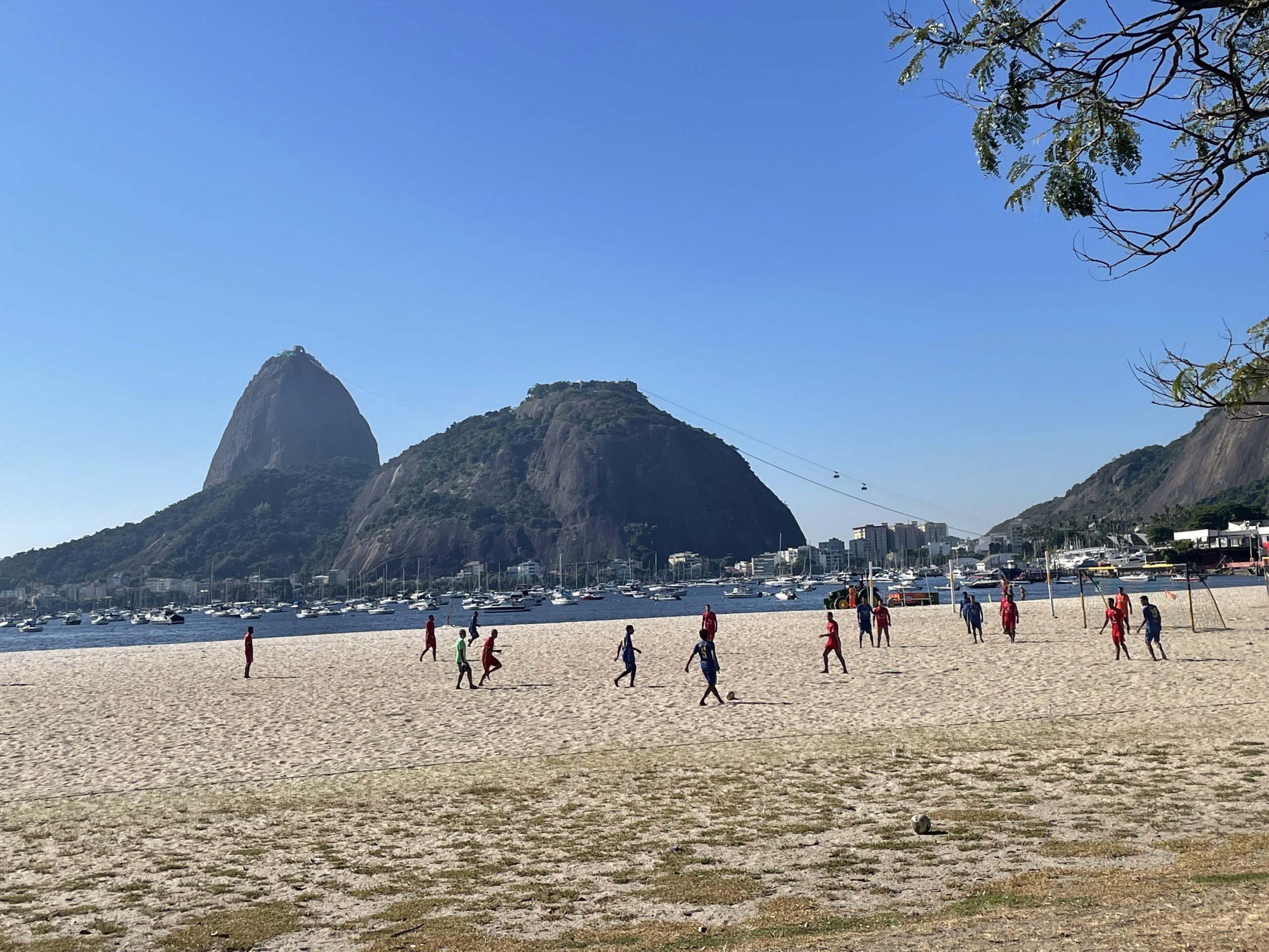 A group of men playing soccer on a sandy beach in Rio de Janeiro.